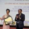 Le ministre vietnamien de la Culture, des Sports et du Tourisme, Nguyen Van Hung, remet la décision de reconduction de Anoa Suzanne Dussol Perran comme ambassadrice du tourisme du Vietnam en France. Photo: VNA