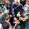 Mme Audrey Lhoest, 1re échevine, et Christos Doulkeridis, bourgmestre de la commune Ixelles, offrent des lanternes aux enfants participant à la fête. Photo : VNA