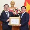 裴青山向山田贵雄大使授予“致力于越南外交事业”纪念章。图自越通社