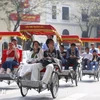 游客坐三轮车参观河内旅游景点。图自越通社