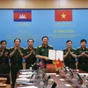 Le général de corps d'armée Huynh Chien Thang, chef adjoint de l'état-major général de l'Armée populaire du Vietnam signe un document sur l'ouverture d'une ligne téléphonique directe entre l'État-major général de l'Armée populaire du Vietnam et le commandement général des forces armées royales du Cambodge. Photo: VNA