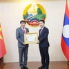Le vice-Premier ministre et ministre des Affaires étrangères du Laos, Saleumxay Kommasith (droite), remet la noble distinction à l'ambassadeur Nguyen Ba Hung. Photo : VNA