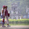 Les touristes étrangers se promènent au bord du lac Hoan Kiem. Photo : VNA