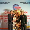 Un représentant du Comité de liaison des volontaires et experts militaires vietnamiens (à droite) offre un annuaire du 75e anniversaire anniversaire de la Journée traditionnelle des soldats volontaires et experts vietnamiens au Lao au consul général du Laos à Da Nang. Photo : VNA