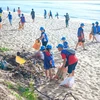 Youths and children clean up a beach (Photo: VNA)