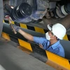 Inspectors check under a truck at Tien Vinh Motor Vehicle Inspection Centre (70-04D) in Tay Ninh province. Older vehicles must undergo strict emission testing under the new law. (Photo: VNA)