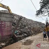 Two residents pass beside the boundary wall of the Burangkeng Final Disposal Site (TPA) which was damaged by a landslide in Bekasi Regency, West Java, November 12. (Photo: Antara/ Fakhri Hermansyah/rwa) 