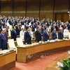 Dirigentes, ex dirigentes del Partido y del Estado y diputados de la Asamblea Nacional, realizan la ceremonia de izamiento de la bandera en la sesión de clausura. (Foto: VNA)