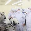 Prime Minister Pham Minh Chinh (centre) visits the semiconductor chip production line of the Hana Micro Vina Co Ltd in the Van Trung Industrial Zone in Bac Giang province. (Photo: VNA)