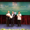 VCBA President Oknha Leng Rithy ( centre) gives flowers to the association’s senior advisor Ly Thuch, who is also Senior Minister and the First Vice President of the Cambodian Mine Action and Victim Assistance Authority at the conference. (Photo: VNA)