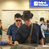 Passengers swipe their cards to board the train as instructed by staff (Photo: VNA)