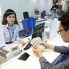 A customer conducts a foreign currency transaction at a banking office (Photo: VNA)