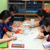 A group of students from Nguyen Du Lao-Vietnamese Bilingual School draw a picture of Uncle Ho. (Photo: VNA)