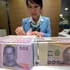 A bank employee counts Thai baht notes in Bangkok, Thailand (Photo: AFP/VNA)