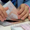 Counting Thai baht at Krung Thai Bank in Bangkok. (Photo: AFP/VNA)