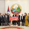 The delegation of the Vietnamese community in Laos presents to the Lao side a token of their aid for those affected by Typhoon Yagi in the country’s northern region. (Photo: VNA)