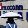 A woman carrying an umbrella walks past the logo of Foxconn outside a company's building in Taipei, Taiwan, Oct. 31, 2022. (Photo: Reuters)