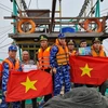 Vietnam Coast Guard officers present the national flag to fishermen at sea. (Photo: VNA)