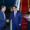 Prime Minister Pham Minh Chinh (C) and his spouse are welcomed by Vice Chairman of the Government Office Nguyen Sy Hiep at the Noi Bai International Airport. (Photo: VGP)