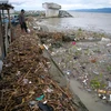 A father and son watch waste sweeping up to the shore near Palu Bay, Central Sulawesi, Indonesia. (Photo: antaranews.com)