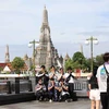Tourists pose for pictures at the Tha Tien pier by the Chao Phraya River opposite the Temple of Dawn (Wat Arun) in Bangkok in June. (Photo: Bangkokpost)