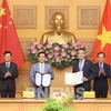 Deputy Prime Minister Tran Luu Quang (R) and Chief Executive of the Hong Kong Special Administrative Region (China) Lee Ka-chiu (L) witness the exchange of the MoU between Vietnam Airlines and the Hong Kong International Airport (HKIA). (Photo: VNA)