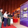 Visitors look at photos at the exhibition (Photo: VNA)