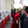 越南外交部副部长阮明恒向国际友人介绍此展上的图片。图自越通社