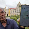 Un jardinero tailandés muestra un mensaje en su teléfono en respuesta a su registro en el sistema de billetera digital. (Foto: bangkokpost.com)