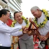 Chairman of the provincial People's Committee Cao Tuong Huy (L) presents a souvenir to David and Tina. (Photo: VNA)