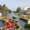 Туристы сидят в круглых лодках, которыми управляют местные жители, наслаждаясь красотой реки. (Фото: Тхюи Лан/Вьетнам+)