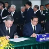 Член Политбюро, президент государства То Лам (слева) и член Политбюро, премьер-министр Фам Минь Тьинь (в центре) пишут в книге соболезнований. (Фото: ВИА)