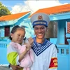 Un soldat de Truong Sa prend dans ses bras une petite fille sur l'île de Truong Sa. Photo: VietnamPlus