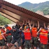 Des secouristes recherchent des personnes dans des maisons effondrées à la suite d’un glissement de terrain causé par de fortes pluies. Photo: VNA