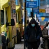 People wearing face masks walk in London, the United Kingdom, on January 26, 2021. (Photo: Xinhua/VNA)