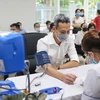 Медицинские работники проверяют здоровье людей, прежде чем делать прививку от COVID-19. (Фото: Vietnam+)