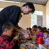 Рэппер Ден Вау аккуратно чистит креветки для школьников в горной местности во время обеда. (Фото: PV/Vietnam+)