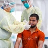 Медицинский персонал берет у трудящегося - мигранта в Сингапуре образец для тестирования на COVID-19 . (Фото: AFP/ВИА)