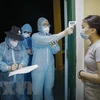 Медсестра измеряет температуру тела у людей, находявшихся в карантинной зоне в провинции Хоабинь. (Фото: ВИА)