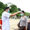 Медицинский работник проверяет температуру тела людей на пограничном пункте пропуска (Фото: ВИА) 