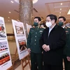 Премьер-министр Фам Минь Тьинь посещает фотовыставку по предотвращению бомб и мин. (Фото ВИА)