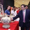 Премьер-министр Вьетнама Фам Минь Тьинь посещает стенд продуктов, получивших национальный бренд Вьетнама 2022 года. (Фото: ВИА)