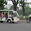 游客们乘坐电瓶车游览河内街道。