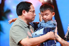 PM Pham Minh Chinh gives encouragement to a boy named Nguyen Quoc Bao, whose father and elder sister were washed away by a flood while the three were crossing a bridge in Cau Treo hamlet of Yen Thuan commune, Ham Yen district, Tuyen Quang province. (Photo: VNA)