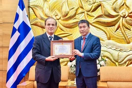 President of the Vietnam Union of Friendship Organisations Phan Anh Son (right) presents the honour to Greek Ambassador to Vietnam Georgios Stilianopoulos at the ceremony in Hanoi on October 15. (Photo: VNA) 