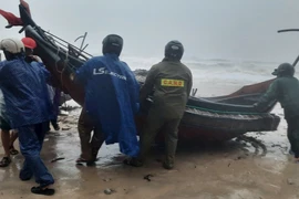 Authorities assist fishermen to move boats onto the shore before Storm Trami hit the mainland in Thua Thien - Hue province. (Photo: VNA)