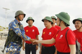 Des représentants du groupe EVN et un soldat sur l'île de Song Tu Tay. Photo : VNA