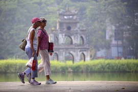 Les touristes étrangers se promènent au bord du lac Hoan Kiem. Photo : VNA