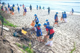 Youths and children clean up a beach (Photo: VNA)
