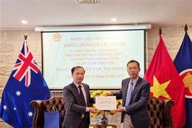 Ambassador Pham Hung Tam (R) hands over 12,700 AUD (8,700 USD) to the delegation to help victims of Typhoon Yagi (Photo: VNA)